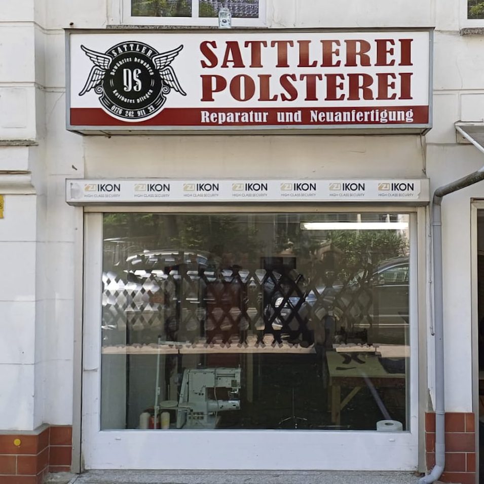 Sattlerei und Polsterei mit Schaufenster und Schild über dem Eingang.